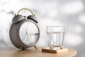 alarm clock next to a glass of water