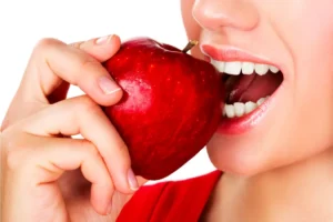 a woman taking a bite of an apple