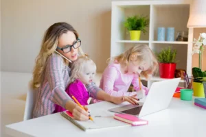 mum juggling work and kids, working at a laptop with two young girls