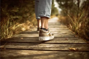 a view of feet walking on a wooden pathway