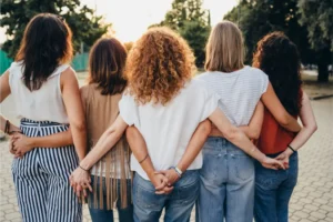 a view from the back of5 female friends holding hands