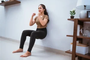 a woman doing a wall sit in the lounge