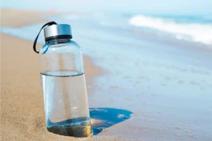 a glass water bottle on the beach