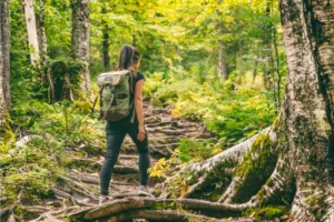 woman wearing a backpack climbing a hill in the forest
