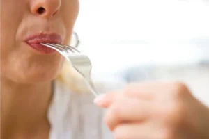 close up of a woman putting a fork into their mouth