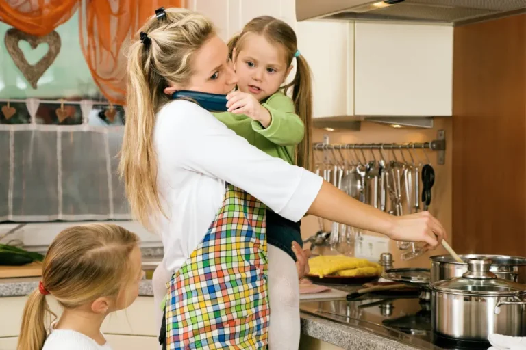 mum cooking whilst on the phone with one child in her arms and another by her side