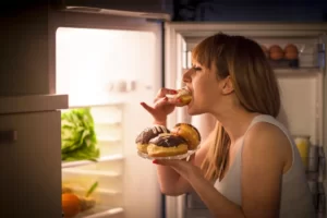 woman snacking in front of the fridge